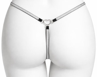 May include: A silver and black thong-style lingerie item. The design includes a heart-shaped detail at the front and a thin strap that goes around the waist. The straps have a glittery appearance.