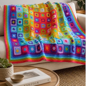 May include: A vibrant, handmade crochet blanket draped over a sofa. The blanket features a colorful patchwork design with squares in shades of red, orange, yellow, green, blue, and purple. The blanket's edges are finished with a rainbow border.