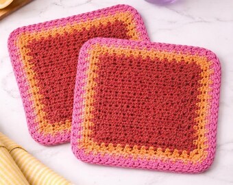 May include: Two square crochet potholders featuring a dark red center, an orange middle border, and a bright pink outer edge. The potholders are crafted with a textured stitch pattern and have rounded corners, displaying a vibrant color gradient.