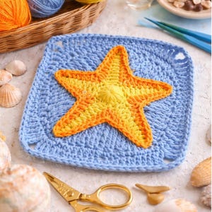 May include: A handmade crochet square featuring a vibrant orange and yellow starfish on a light blue background. The square is surrounded by seashells, gold scissors, and yarn in a basket, evoking a beach theme.