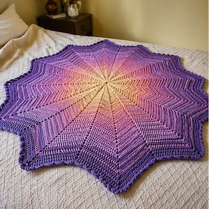 May include: A handmade, star-shaped crochet blanket in shades of purple, pink, and yellow. The blanket features a textured stitch pattern radiating from the center. The edges are scalloped, adding a decorative touch. This cozy blanket is perfect for a bed or sofa.