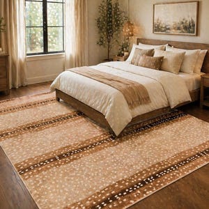 May include: A beige and brown patterned area rug in a bedroom setting. The rug features a spotted design with dark brown stripes. The bedroom includes a wooden bed frame, a dresser, and a window with natural light.