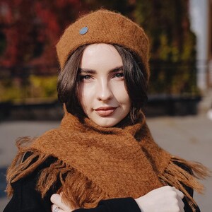 A brown bell-shaped hat and a triangular scarf with fringe. Set is knitted using straight needles and a crochet hook in a Chanel pattern.
