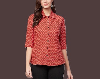 May include: A red button-down shirt featuring a repeating small geometric pattern in white and gold. The shirt has a classic collar, three-quarter length sleeves, and a straight hemline. The front is secured with a vertical row of dark buttons.