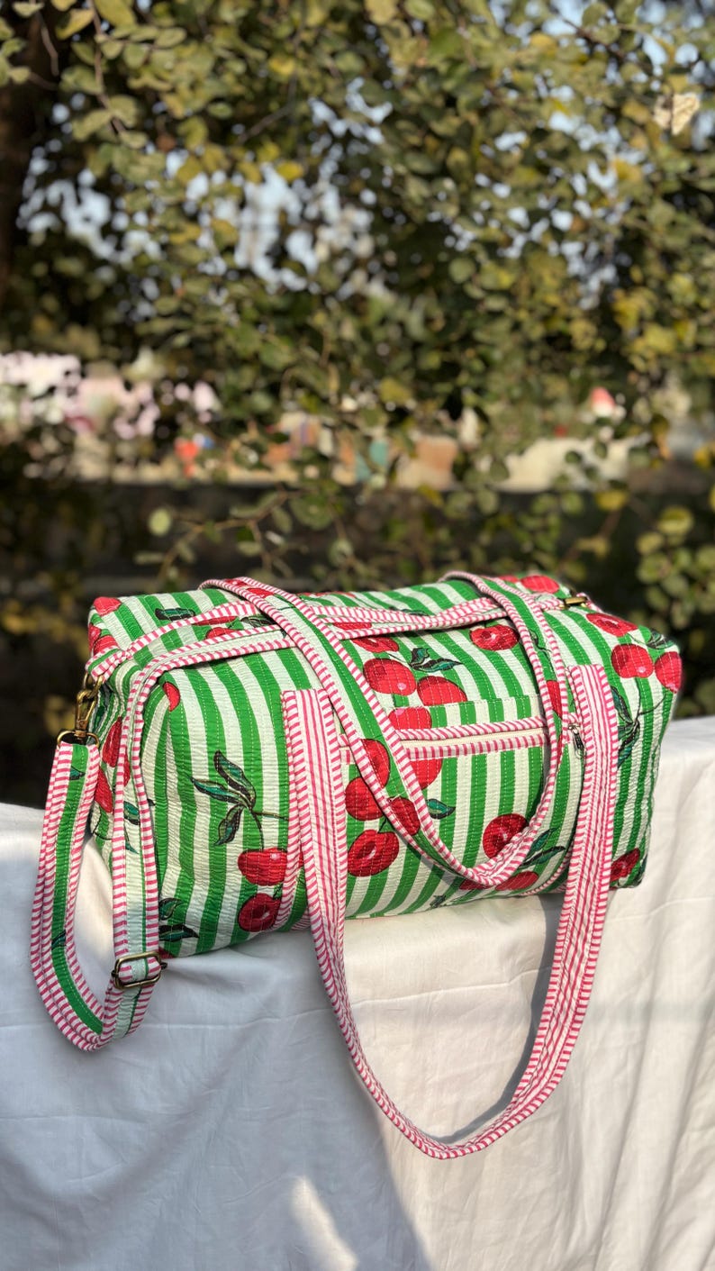 Puede incluir: Bolso de viaje rectangular a rayas verdes y blancas con estampado de cerezas. El bolso tiene una correa a rayas rojas y blancas y un peque&ntilde;o bolsillo. Dise&ntilde;ado para viajar, tiene un estilo informal.