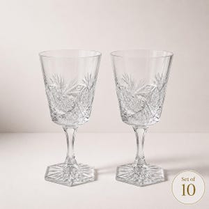 May include: A set of ten clear crystal wine glasses featuring intricate starburst and cross-hatch cut patterns on the bowl. Each glass has a faceted hexagonal base and a slender stem, showcasing a reflective, transparent design throughout the set.