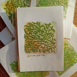 May include: A selection of handmade greeting cards with a green and yellow abstract design. Each card displays a unique pattern reminiscent of foliage. The cards are on white paper with the text "Fructicose 2023-50" in the bottom corner.