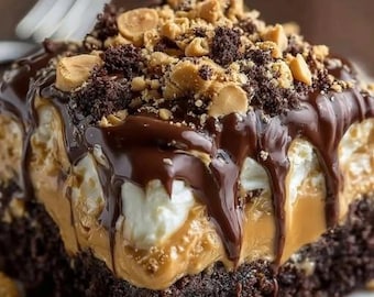 Puede incluir: Una porción cuadrada de pastel de chocolate con capas de un relleno espeso de mantequilla de maní color canela y crema blanca. La parte superior está cubierta con ganache de chocolate negro, migas de galleta y maní tostado.