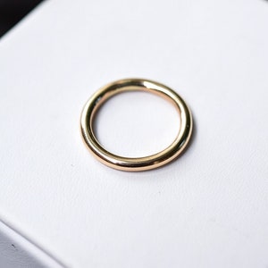 Może przedstawiać: Prosty złoty pierścień o gładkiej, zaokrąglonej powierzchni.