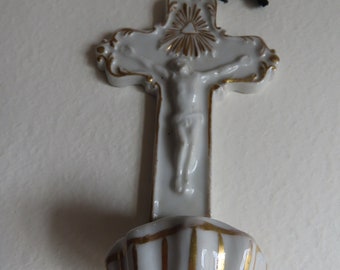 Peut inclure: Crucifix en porcelaine blanche avec un motif peint en or. Le crucifix représente une figure de Jésus-Christ et une base en forme de coquille.