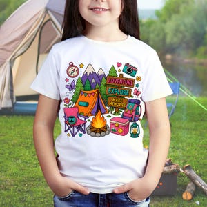 May include: White t-shirt with a vibrant camping design. The illustration shows a tent, campfire, mountains, and the text "Adventure, Explore, Make Memories." A compass, camera, and backpack are also included.