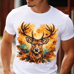 May include: White t-shirt featuring a detailed illustration of a deer with large antlers. The deer is depicted with brown fur and is set against a backdrop of orange, yellow, and green brushstrokes, creating a textured effect.