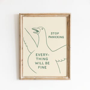 May include: A framed art print with a cartoon bird illustration in green on a cream background. The print includes the text "STOP PANICKING, EVERYTHING WILL BE FINE". The frame is a light brown color.