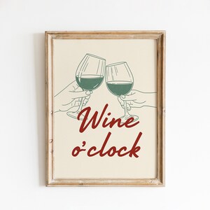 May include: Framed print with a beige background featuring two wine glasses clinking, held by hands. The text "Wine o'clock" is written in a burgundy script font. The image has a rustic, vintage aesthetic.