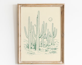 May include: A framed print depicting a desert scene with green cacti and a full moon. The artwork is a line drawing style, set against a cream-coloured background. The frame is a light wood colour.