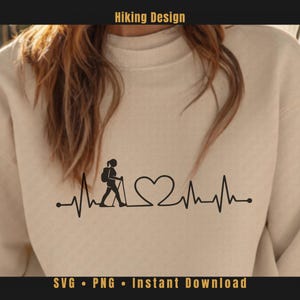 Könnte beinhalten: Beiges Sweatshirt mit schwarzer Grafik eines Wanderers in einer Herzschlaglinie, die ein Herz bildet. Der Text "Hiking Design" steht oben. Der Text unten lautet "SVG • PNG • Instant Download".