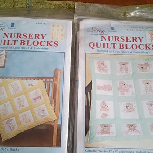 May include: Two packages of nursery quilt blocks for cross stitch and embroidery. One package features a quilt with baby duck designs, and the other features teddy bear designs. Each package is labeled with the text "Nursery Quilt Blocks".