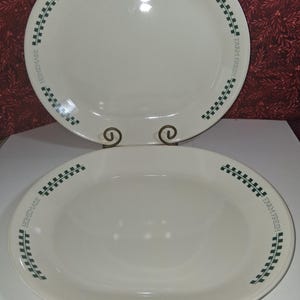 May include: Two oval, off-white platters. Each platter has a green border design with the words "HOMEMADE" and "FARM FRESH" in green. The platters are displayed on a white surface.