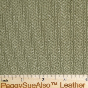May include: A close-up of a green fabric with a textured pattern of small triangles. The fabric is measured with a ruler that reads "PeggySueAlso TM Leather" and has markings in inches.