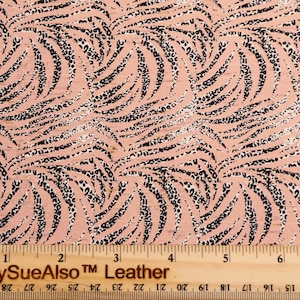 May include: Pink fabric with a black and white swirl pattern. The fabric has a textured surface and a repeating pattern of small black and white dots. The fabric is measured with a ruler that reads "PeggySueAlso™ Leather".