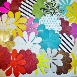 May include: Assortment of colorful felt flower shapes in various sizes and patterns. The flowers are made of felt and have a variety of textures and designs.