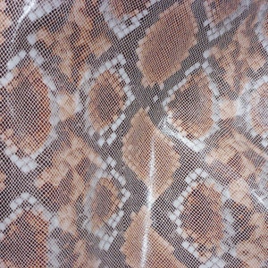 May include: Close-up of a brown and white snakeskin pattern fabric. The fabric has a textured, woven appearance.