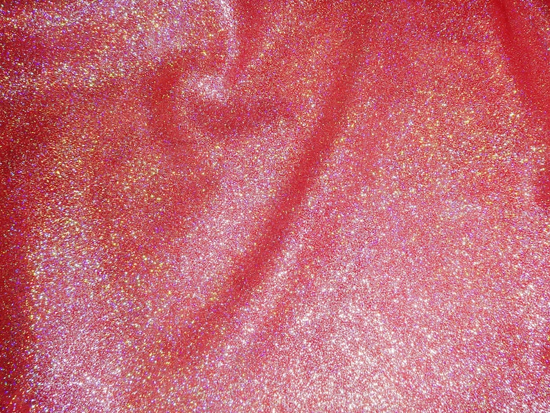 Puede incluir: Primer plano de una tela roja con purpurina iridiscente. La purpurina est&aacute; esparcida por la tela, creando un efecto brillante.