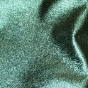 May include: Close-up of a textured, teal green leather fabric. The leather has a subtle sheen and a slightly wrinkled appearance.