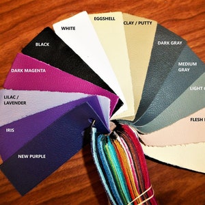 May include: A color chart of leather swatches in various shades of purple, gray, and beige. The swatches are arranged in a circle with the names of each color printed on the top of each swatch.