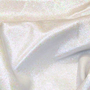 Puede incluir: Primer plano de una tela brillante e iridiscente. El material tiene una superficie texturizada y refleja un espectro de colores, incluyendo toques de rosa, verde y amarillo. La tela está drapeada, creando pliegues y sombras suaves.