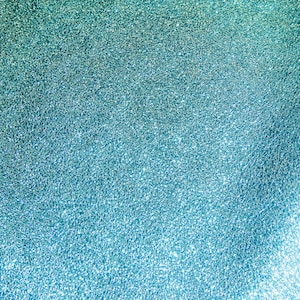 May include: A close-up of a blue sparkly fabric with a subtle gradient from light to dark blue.