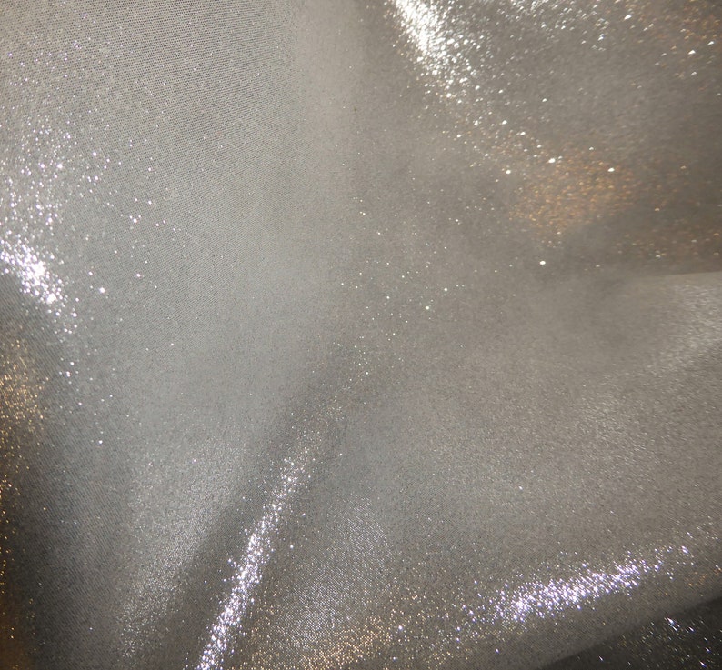Op de afbeelding: Een close-up van een zilveren stof met een glinsterende, glitterende textuur.