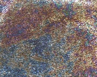 May include: Close-up of iridescent fabric with a textured, scaly pattern. The fabric has a metallic sheen and appears to be made of small, overlapping scales.