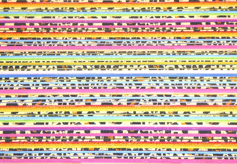 May include: A close-up of a stack of colorful nail files with a leopard print design. The files are arranged in a rainbow pattern, with each file having a different color.