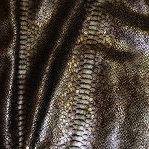 May include: Close-up of a textured fabric with a snakeskin pattern in shades of brown and gold.