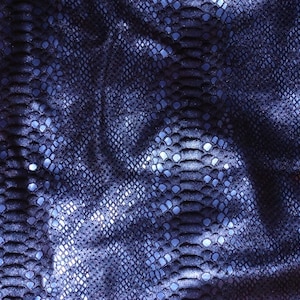 May include: Close-up of a blue snakeskin fabric with a textured pattern. The fabric is wrinkled and has a slight sheen.