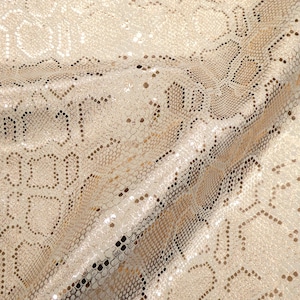 May include: A close-up of a beige fabric with a snakeskin pattern. The fabric has a subtle shimmer and is made of a soft, textured material.