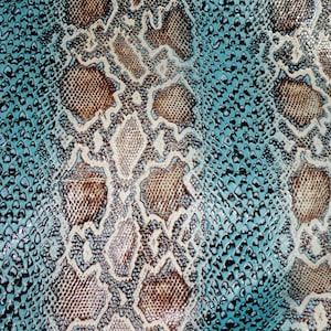 May include: Close-up of a textured snakeskin pattern. The design features a mix of brown, cream, and turquoise blue scales. The pattern is detailed and appears to be a repeating design, suitable for fashion or craft projects.
