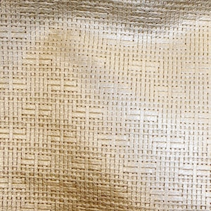 Puede incluir: Primer plano de una tela tejida de color dorado con un brillo sutil. La tela tiene una textura en forma de cuadrícula.