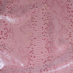 May include: Pink snakeskin pattern with a scale-like texture. The material has a glossy finish and a subtle shimmer. The design features a repeating pattern of diamond shapes and small perforations, creating a unique visual effect.