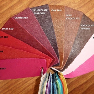 May include: A leather color chart with 12 different shades of red, pink, brown, and tan. The colors are labeled with names like "Raspberry", "Valentine", "Dark Red", "Chocolate Maroon", "Oak Tan", "Milk Chocolate", "Chocolate Brown", "Soft Pink", and "Hot Pink/Fuchsia".