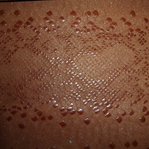 May include: Close-up of a brown leather texture with a repeating diamond pattern.