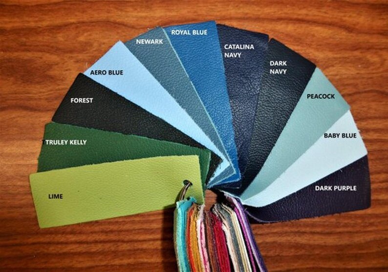 May include: A leather color chart with 12 different shades of blue, green, and purple. The colors are arranged in a semi-circle, with the names of each color printed on the swatches.