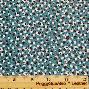 May include: Teal-colored leather sheet with a speckled pattern of black and white spots. The leather has a textured surface. A wooden ruler with inch measurements is at the bottom of the image. The text "PeggySueAlso Leather" is printed on the ruler.