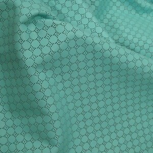 May include: Close-up of turquoise fabric featuring a repeating pattern of small, evenly spaced circles. The fabric has a perforated design, with tiny holes creating the pattern. The material is soft and appears draped, with visible folds and shadows.