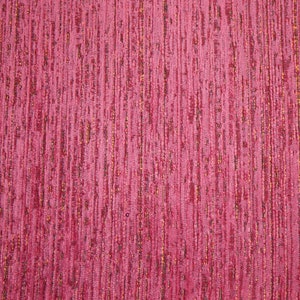 May include: Close-up of a textured fabric with a pink and gold color scheme. The fabric has a vertical striped pattern.