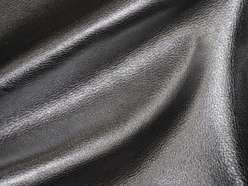 May include: Close-up of a black leather fabric with a textured surface.
