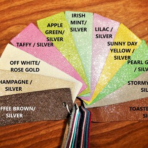 May include: A color swatch fan featuring various glittery fabric samples. Colors include Taffy/Silver, Apple Green/Silver, Irish Mint/Silver, Lilac/Silver, Sunny Day Yellow/Silver, Pearl Green/Silver, Stormy Taupe/Silver, and Toasted Topaz/Silver. The samples are attached to a metal ring.