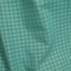 May include: Close-up of a teal fabric with a perforated pattern. The fabric has a soft texture and is draped, showing the intricate design of small, evenly spaced holes arranged in a repeating circular pattern.