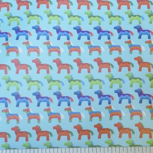 May include: A light blue background with a repeating pattern of colorful horse figures. The horses are in shades of red, orange, green, blue, and purple. The design is reminiscent of a piñata.